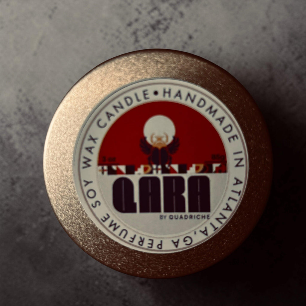 Ambrosia  QARA by Quadriche Discovery Travel 3oz Candle in a tin with a label on a concrete surface cherry blossom  fragrance scent