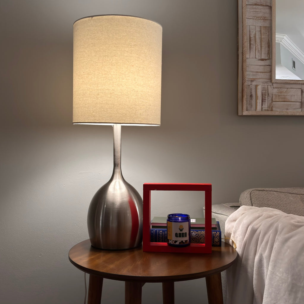 Candle, green sponge, and rose gold tool on a wooden surface QARA SACRED GROUND scented candle earthy scent natural ingredients and lab tested fragrance oil front soy coconut wax 