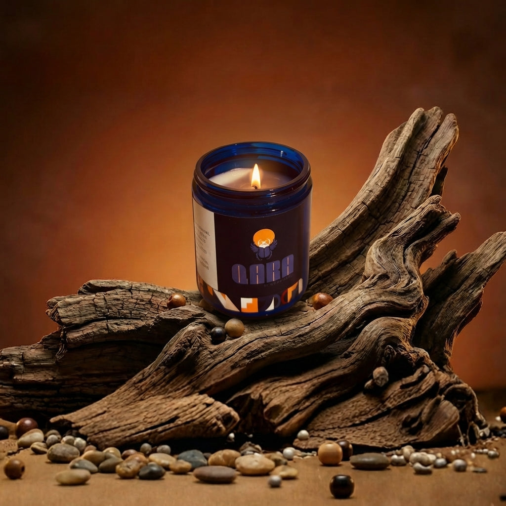 Scented candle in a cobalt blue glass jar signature scent by Quadriche on a piece of driftwood with a warm brown background