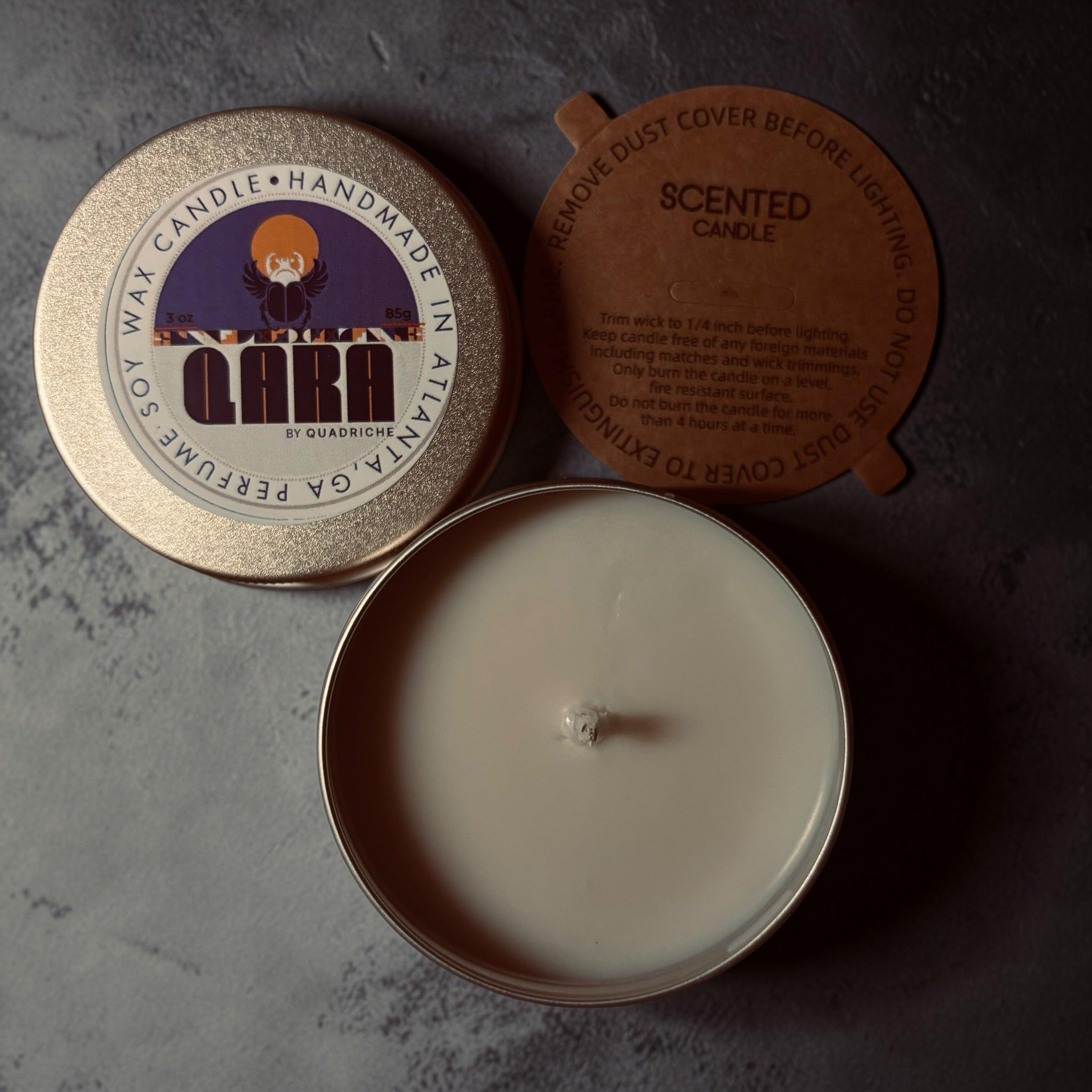 Ember Ink QARA by Quadriche Discovery Travel 3oz Candle in a tin with a label on a concrete surface peppercorn violet pine sage juniper leather fragrance scent