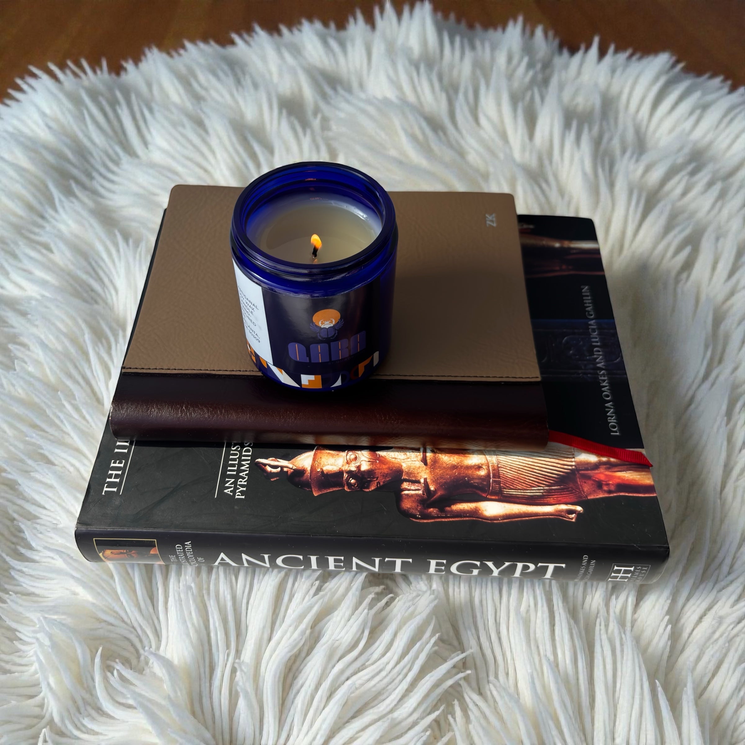 Candle on top of a book titled 'Ancient Egypt' on a fluffy sheep shaggy carpet
