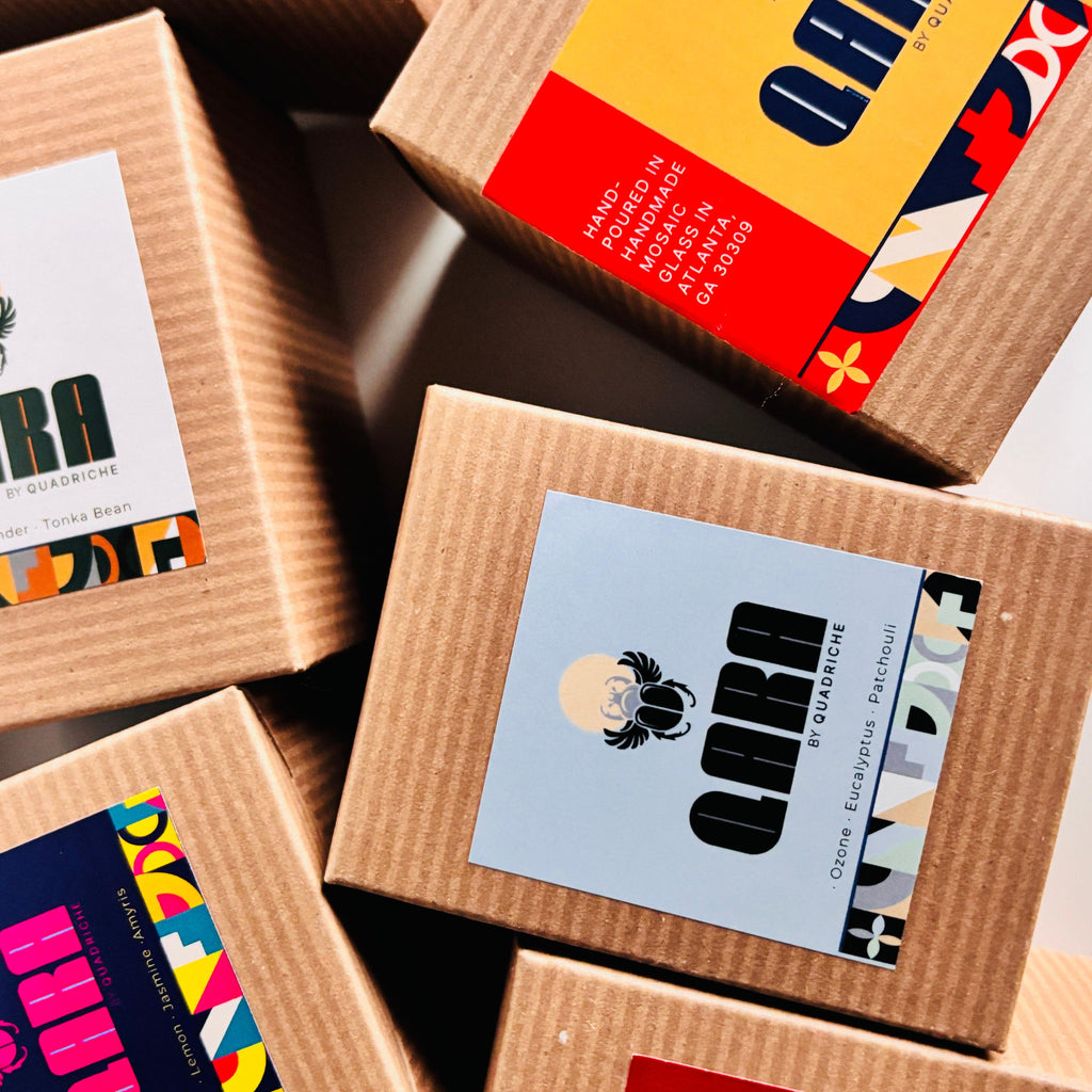 Cardboard box packaging with colorful labels featuring the brand 'QARA by Quadriche' on a dark surface.