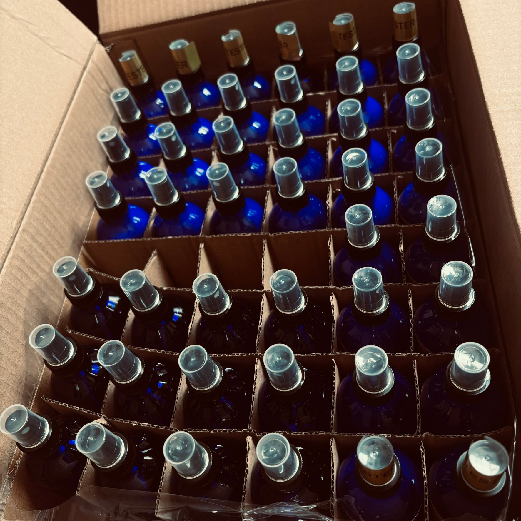 Quadriche fine home fragrance in cobalt blue glass bottles in a box showing large quantities