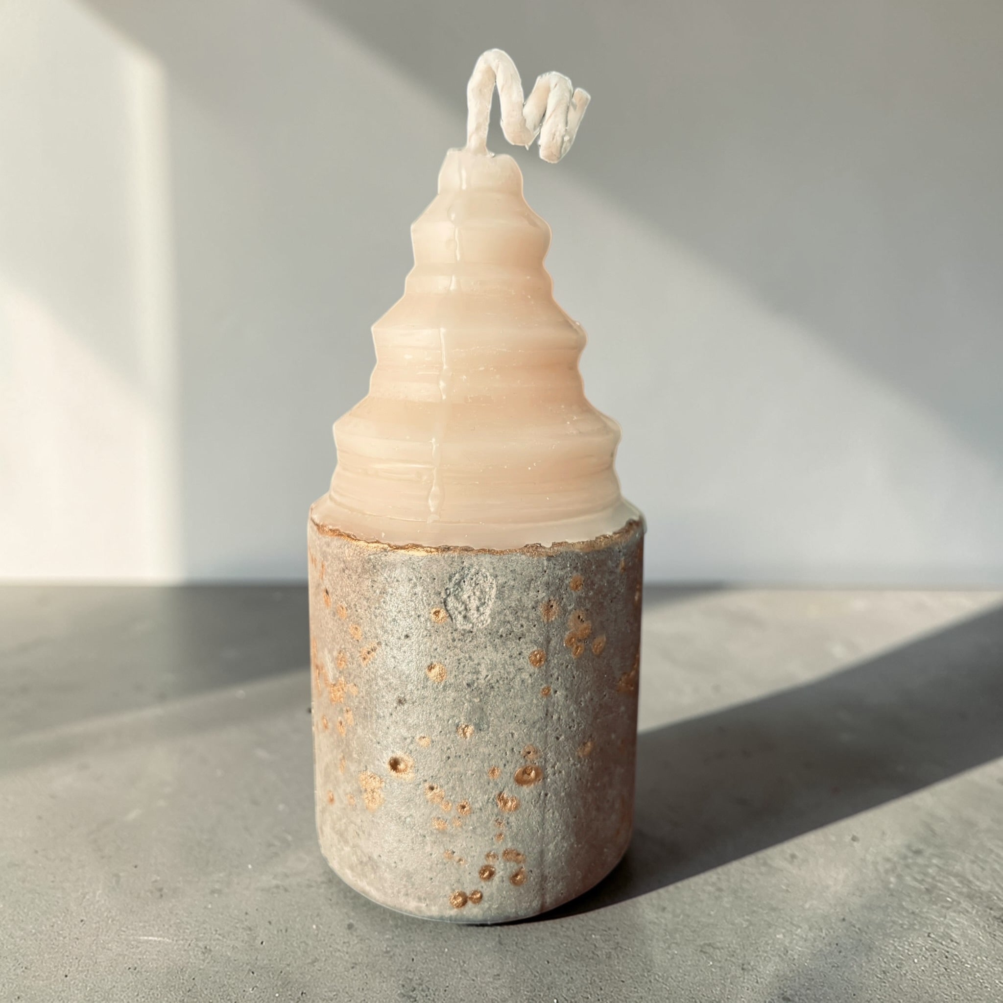 Layered sculptural concrete candle with stacked soy wax form and gold-accented base, architectural candle design by Quadriche