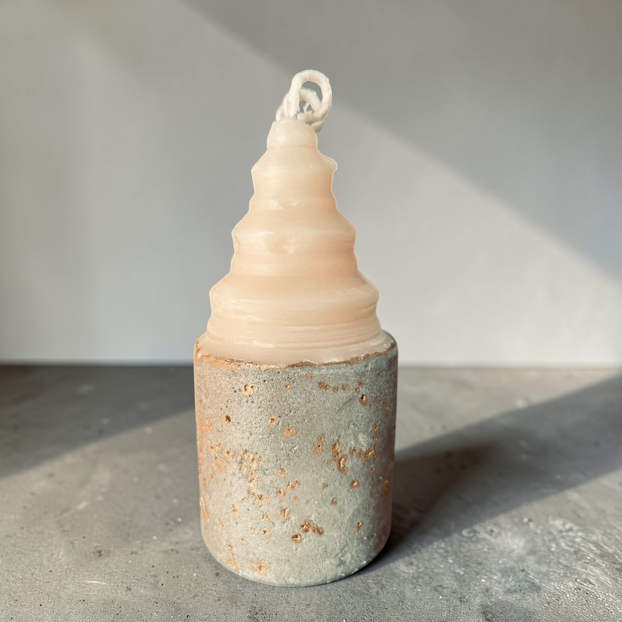 Layered sculptural concrete candle with stacked soy wax form and gold-accented base, architectural candle design by Quadriche side view