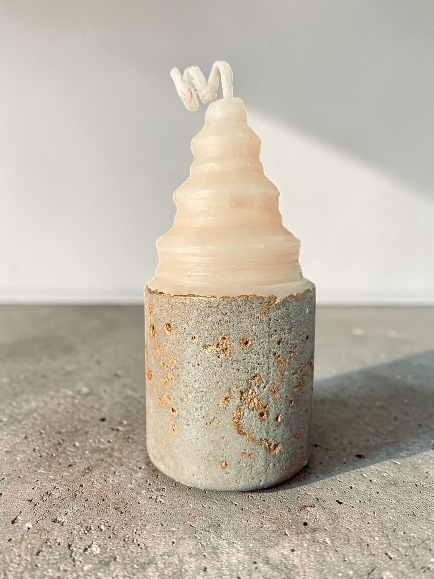 Layered sculptural concrete candle with stacked soy wax form and gold-accented base, architectural candle design by Quadriche front view
