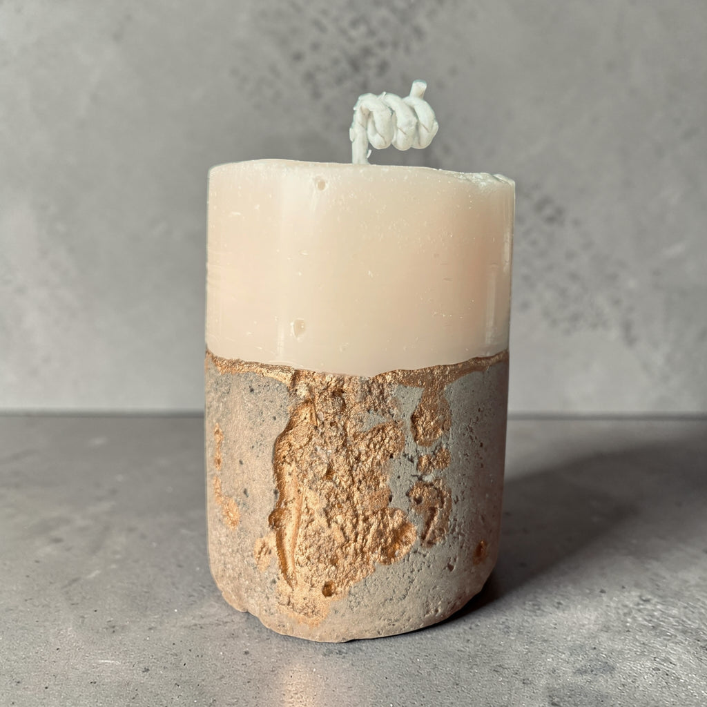 Tall stacked wax concrete candle with textured stone base and gold detailing, modern sculptural home fragrance candle front view
