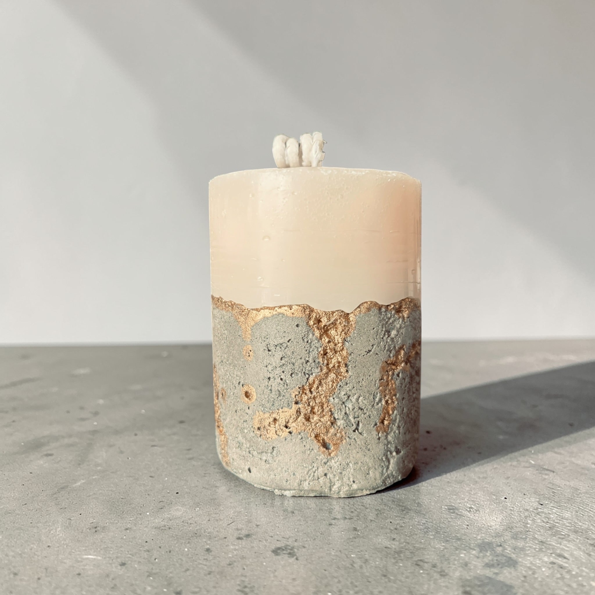 Tall stacked wax concrete candle with textured stone base and gold detailing, modern sculptural home fragrance candle side view made in Atlanta