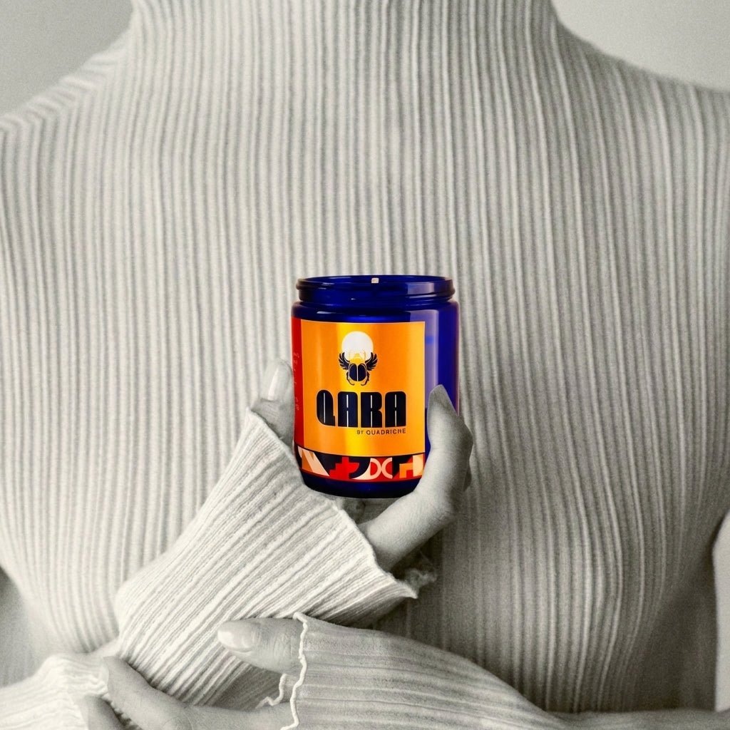 Person holding a cobalt blue glass candle labeled 'QARA' against a neutral background